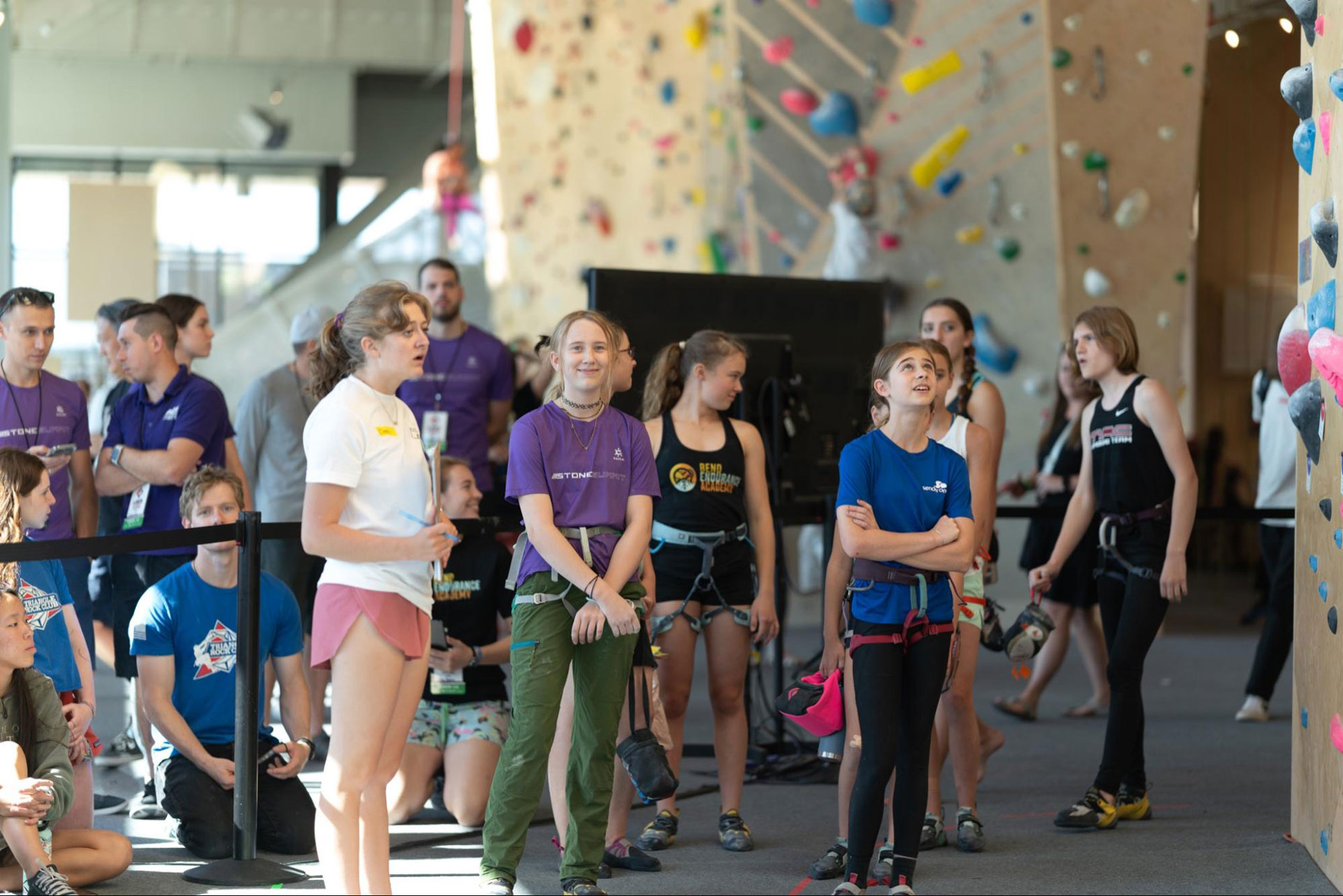 Female youth athletes harnessed up and waiting to climb