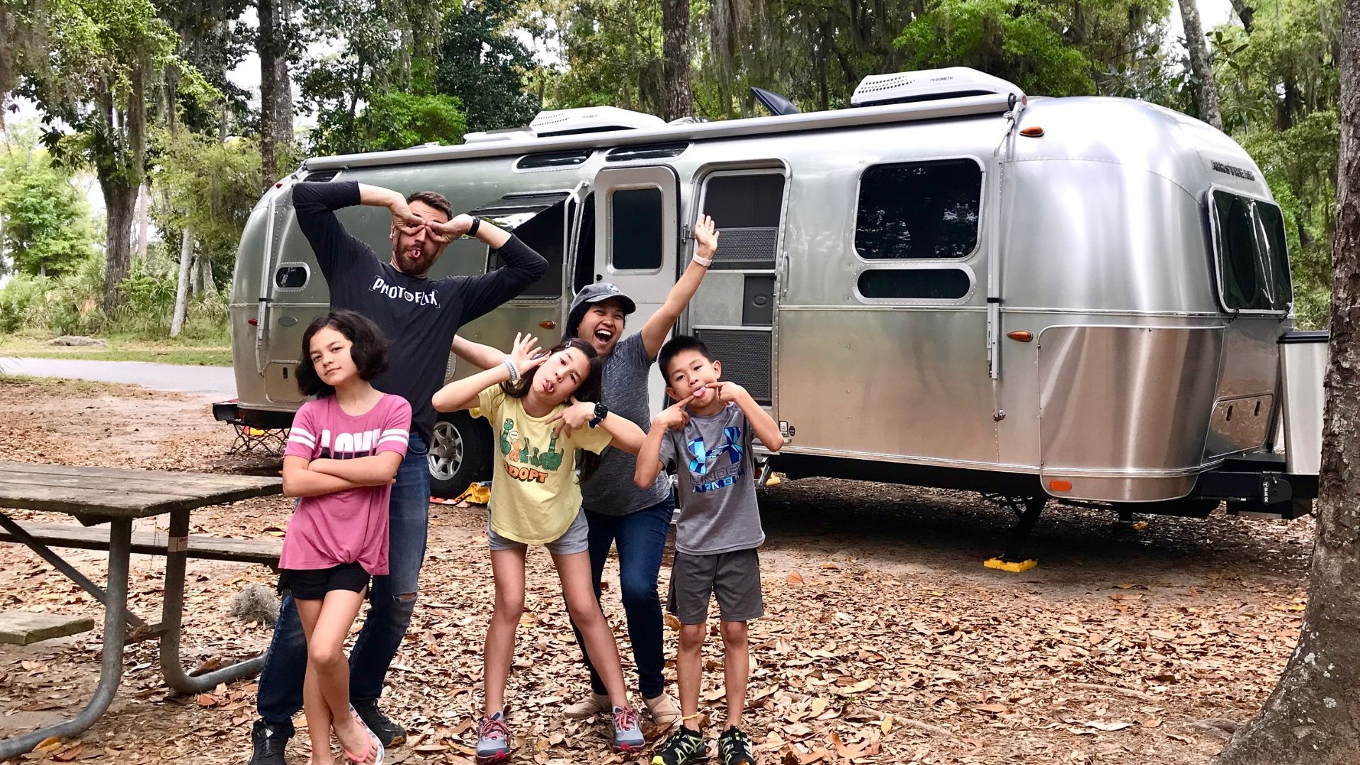 The Blume family posing for a photo, with their airstream trailer in the background