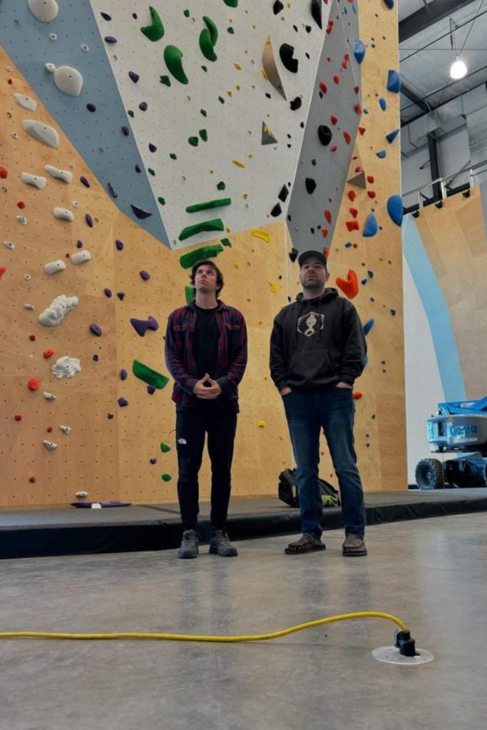 Nickolas Gagliardi standing in front of a climbing wall inside a gym