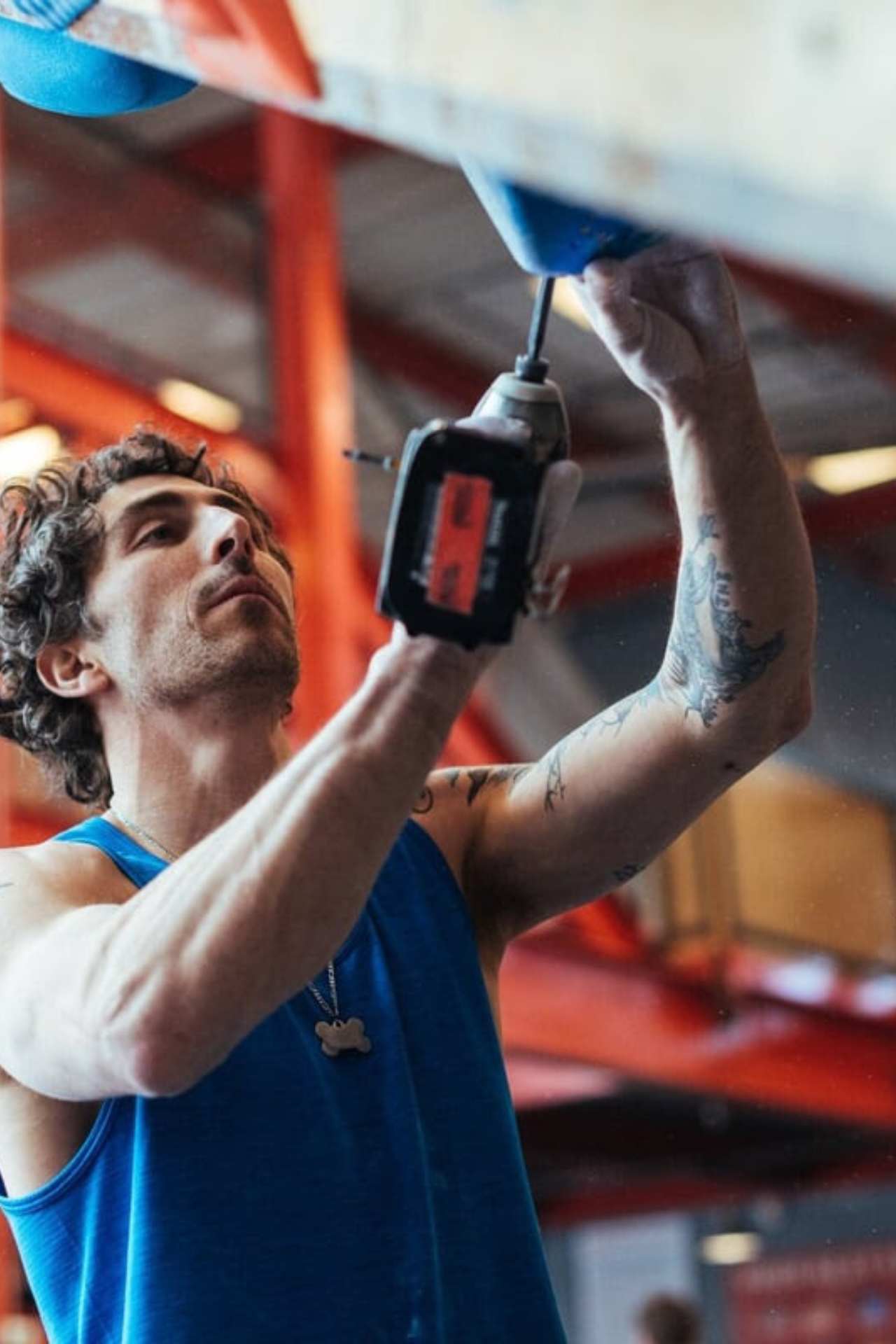 Mike drilling a hold onto the wall inside a gym