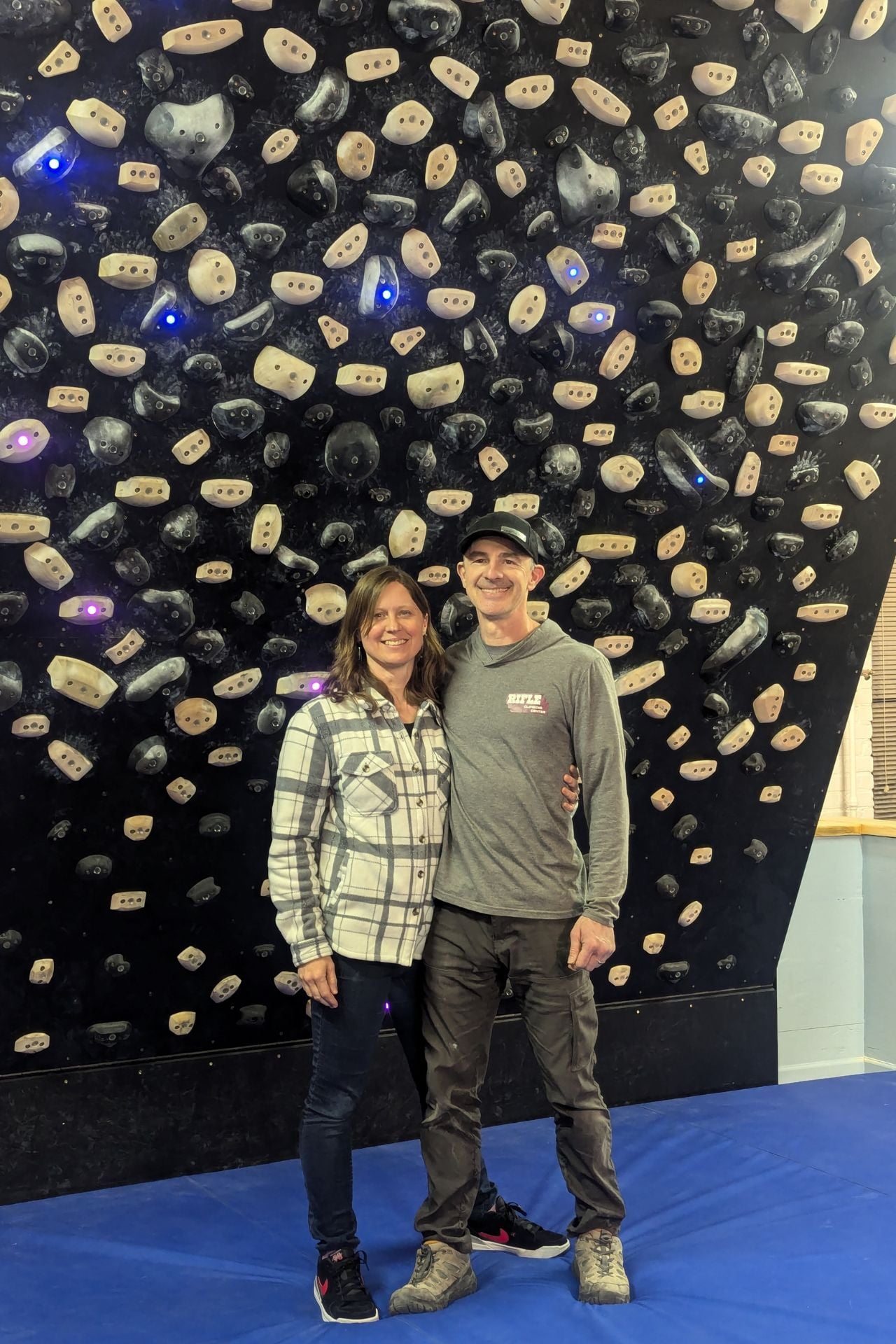 Rifle Climbing Center owners Carissa and Jason Marshall standing in front of a board at the gym