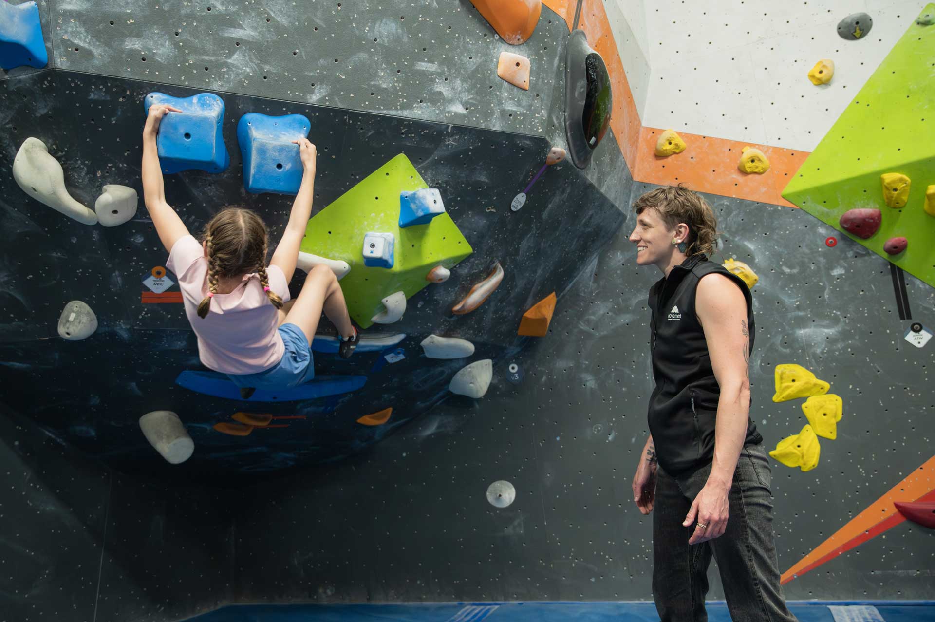 Smiley coaching a youth climber bouldering in the gym