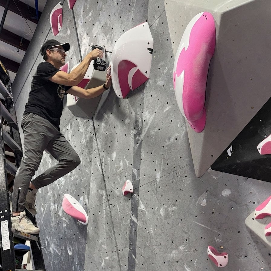 Foose on a ladder setting a bouldering problem with dual-tex grips