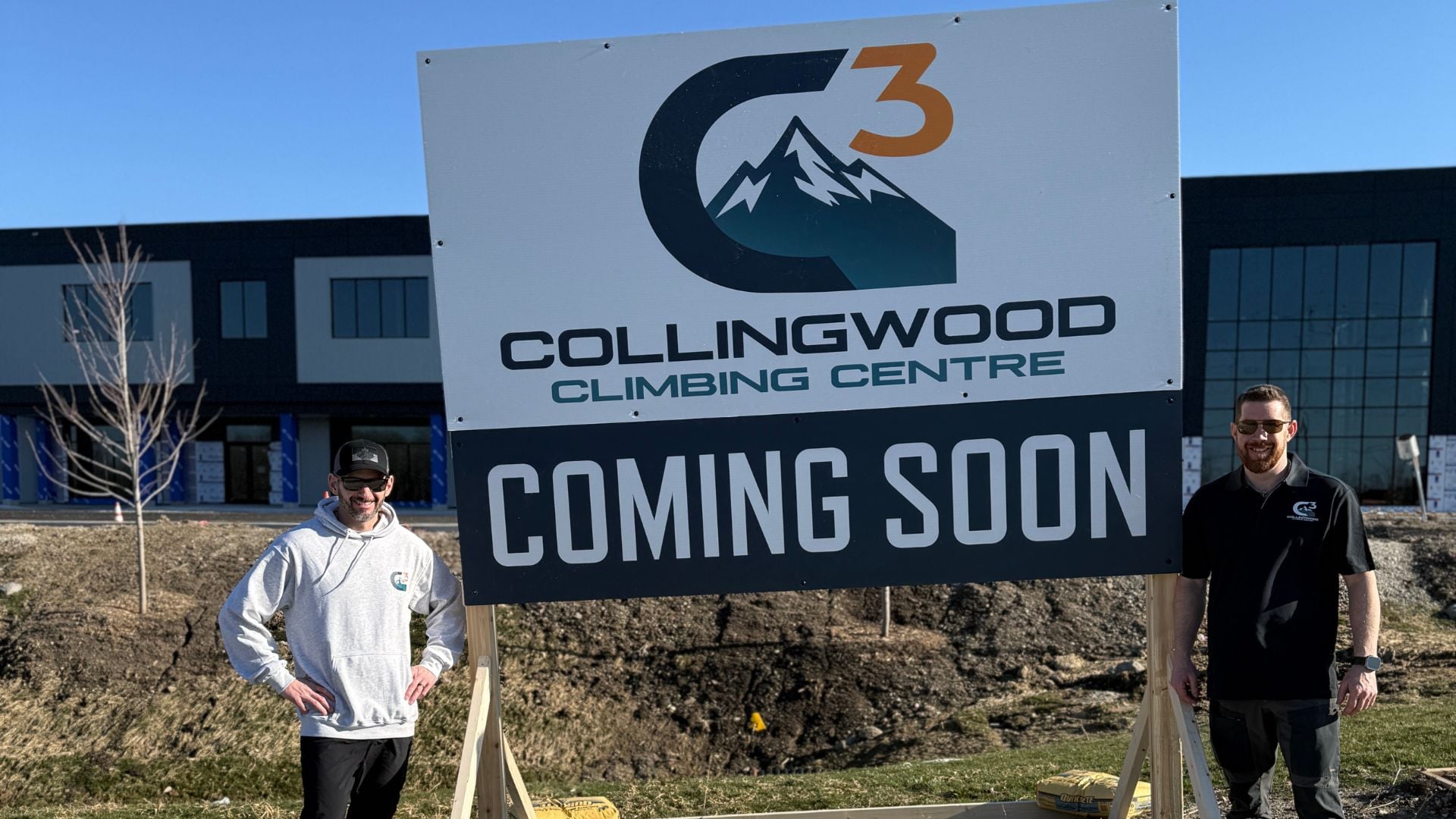 Marc and Mike Drake standing in front of a Collingwood Climbing Centre sign