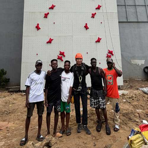 Co-founder Peter Zhang standing alongside Lagos community members in front of Weland's speed wall