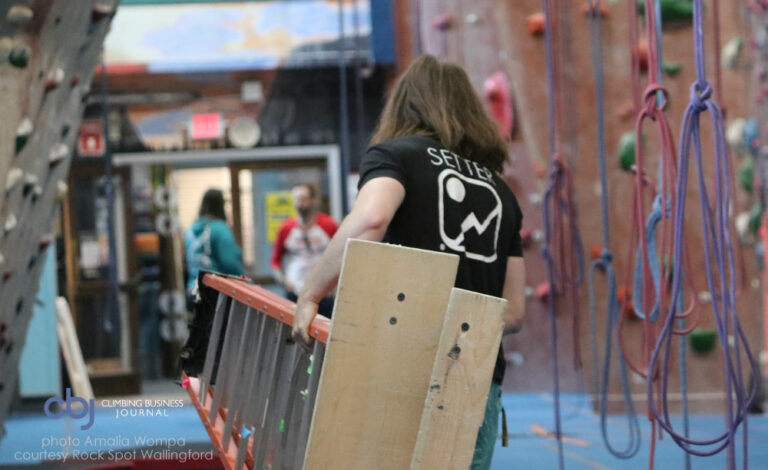 routesetter in gym carrying ladder